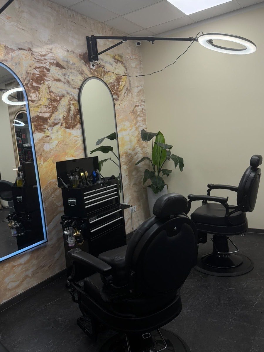 Herrenbereich mit klassischen Barber-Stühlen vor einer Marmoroptik-Wand